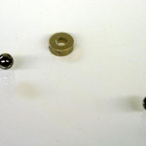 Roll one of the ball bearings at a grazing angle across the ring magnet.  Watch the ball bearing either be deflected to a different direction, or orbit the magnet. 