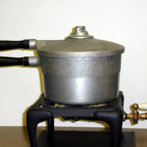 Place the pressure cooker on the gas burner.  A pressure gauge and thermometer may be used to monitor the temperature of boiling as a function of pressure.