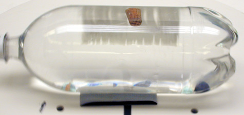 2-Liter pop bottle filled with water, marbles, cork on a rotating air table